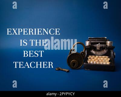 Vintage typewritter and padlock with the word EXPERIENCE IS THE BEST TEACHER on blue background Stock Photo