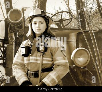 A Female Fire Fighter stands in front of an abandoned American La France V12 Fire Truck. Possible use as book covers, magazine covers, web page illus. Stock Photo