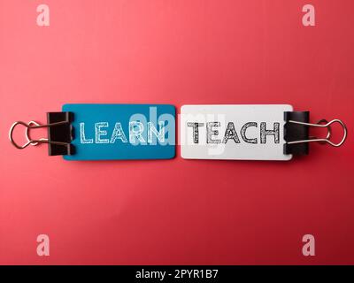 Paper clips and wooden board with the word LEARN TEACH on red background Stock Photo