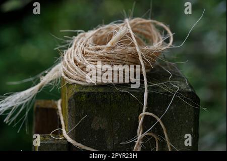 Some string or twine has been loosely wound and put on a post in the garden waiting for its next job Stock Photo