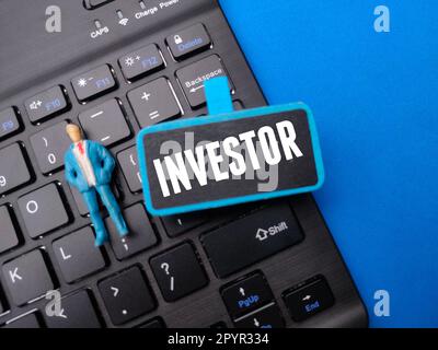 Wireless keyboard and miniature people with the word INVESTOR. Stock Photo