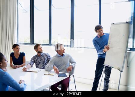 Boardroom strategists. A businessman doing a presentation using a whiteboard during a boardroom meeting. Stock Photo