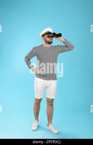 Sailor with binoculars on light blue background Stock Photo