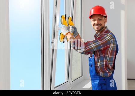 Worker using suction lifters during plastic window installation indoors Stock Photo