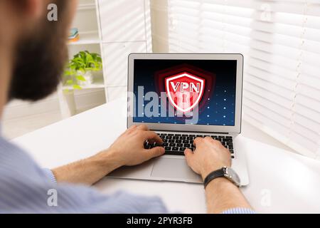 Man using laptop with switched on VPN at white table, closeup Stock Photo