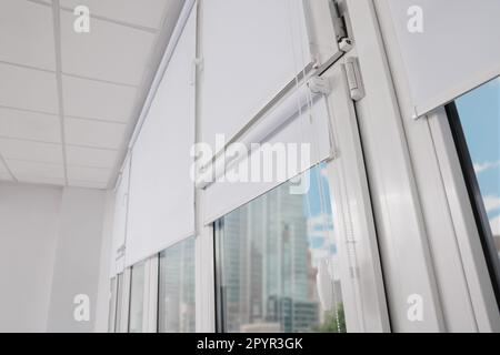 Plastic windows with white roller blinds indoors Stock Photo