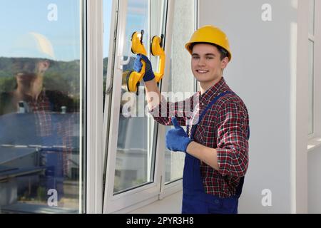 Worker using suction lifters during plastic window installation indoors Stock Photo