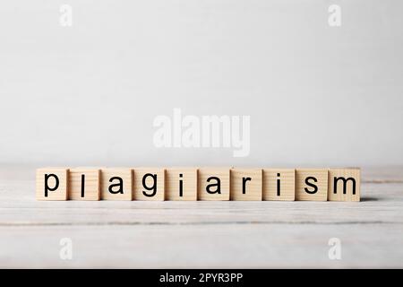 Wooden cubes with word Plagiarism on white table, space for text Stock Photo