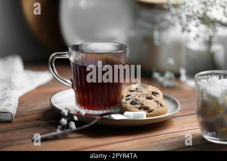Cup of freshly brewed tea and delicious cookies on wooden table Stock Photo