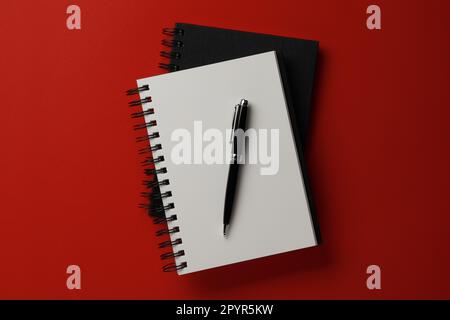 Notebooks and pen on red background, top view Stock Photo