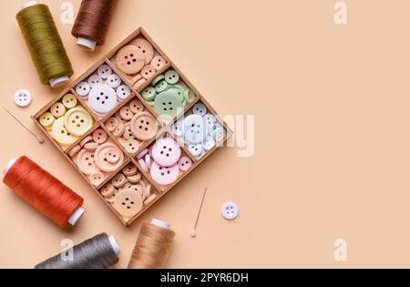 Composition with different buttons, thread spools and ball pins on color background Stock Photo