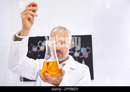 The measurements need to be perfect. a mature male scientist conducting an experiment in his lab. Stock Photo