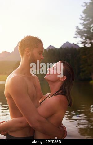 Lakeside love. an affectionate young couple hugging while swimming in a lake. Stock Photo