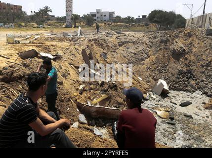 Gaza, Palestine. 03rd May, 2023. Palestinians sit near a crater caused by Israeli air strikes in Deir al-Balah, central Gaza Strip. Credit: SOPA Images Limited/Alamy Live News Stock Photo