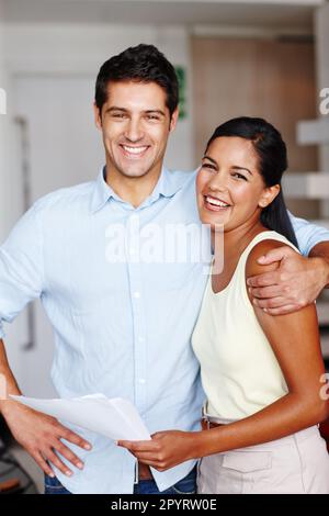 Friendship in the office. Two friendly colleagues hugging one another in the office. Stock Photo