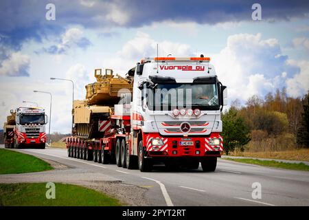 Mercedes-Benz truck hauls American M1 Abrams military tank on semi trailer. Convoy of 3 exceptional load transports. Salo, Finland. April 28, 2023. Stock Photo
