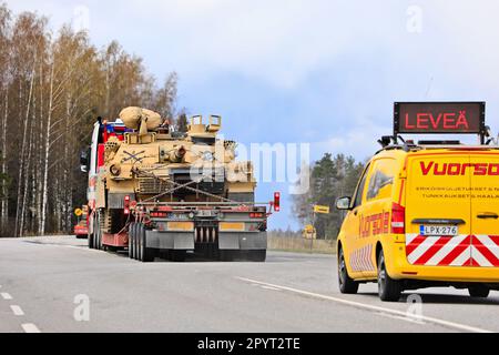 Exceptional load transport of American M1 Abrams military tank in traffic with escort vehicle. Convoy of 3 transports. Lieto, Finland. April 28, 2023. Stock Photo