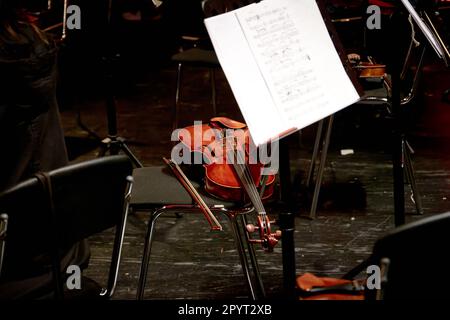 Image of a wooden stringed instrument violin lies on a chair Stock Photo