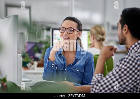 Sharing ideas for a cohesive strategy. Male and female colleagues discussing ideas at their work station. Stock Photo