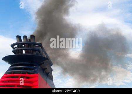 Polluting smoke comes out of the smokestacks of a giant ship Stock Photo