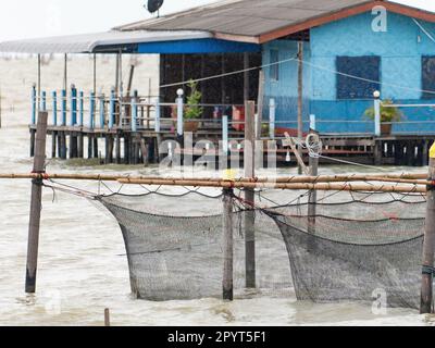 Fish farm at Songkhla Lake in Songkhla, south of Thailand on a rainy day. Shallow depth of field with the nets in the foreground in focus. Fisherman's Stock Photo