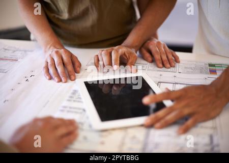 Using all the tools of the architectural trade. a group of designers using a digital tablet. Stock Photo