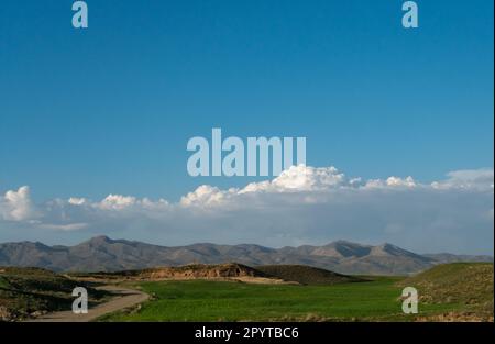 The view of the mountain and the road on a spring day when the sky is blue and there are many clouds Stock Photo