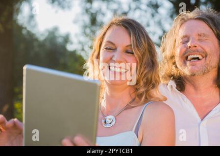 Couple laughing together while looking at tablet, Bavaria, Germany Stock Photo