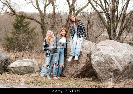 Three happy young happy teenagers hugging on a mountain road stock photo -  OFFSET