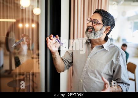 Happy mature male entrepreneur holding felt tip pen at cafe Stock Photo