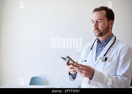 Male healthcare worker using smart phone while standing in clinic Stock Photo