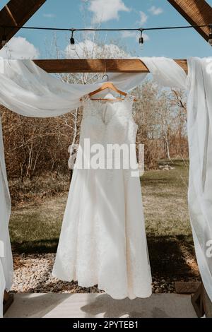 Full length lace wedding dress hanging in the spring sunshine Stock Photo