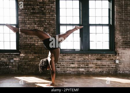 Black woman dancer in handstand split pose leg extension Stock Photo