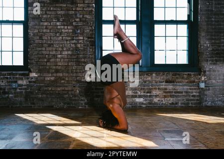 African American black woman dancer in shoulder stand in exposed brick Stock Photo