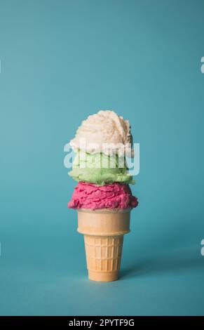 Ice cream cone with three scoops on a blue background. Stock Photo