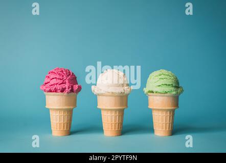 Three ice cream cones in a variety of flavours on blue background. Stock Photo