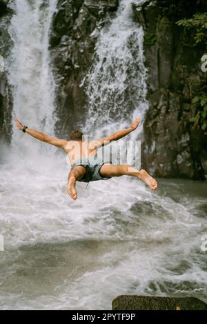 A man jumps from a waterfall. Bali. Stock Photo