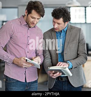 Where brilliant ideas begin. two male coworkers taking over digital tablets in an office. Stock Photo