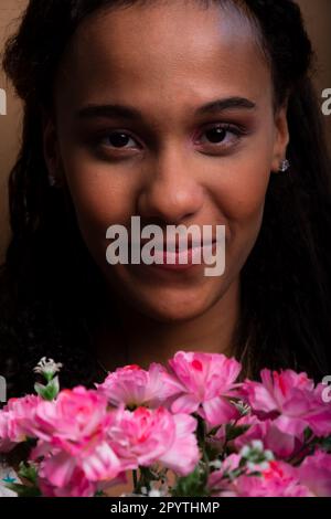 Close-up portrait of pretty teenage girl with bouquet of flowers. Isolated on brown background. Stock Photo