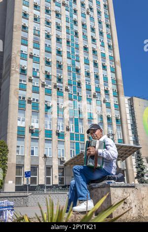 CHISINAU, MOLDOVA-MAY 12, 2022: Old Man Musician Busking Playing accordion Outdoors In Central Street Stock Photo