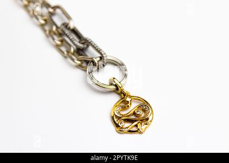 An ornately designed silver necklace featuring a detailed golden pendant on the white background Stock Photo