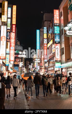 TOKYO, JAPAN - APRIL 8, 2023: People walking in Shibuya shopping area in drizzle evening Stock Photo