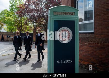 Eton, Windsor, Berkshire, UK. 5th May, 2023. Eton College boys walk past a Coronation crest on a telephone box marking the occasion of the Coronation of the King. The son's of King Charles III, Prince William and Prince Harry, went to school at the famous Eton College public school in Eton, Windsor. Credit: Maureen McLean/Alamy Live News Stock Photo