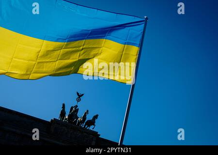 'Germany, Berlin, March 13, 2022: The Ukrainian flag can be seen in front of the Brandenburg Gate as tens of thousands people rally under the slogan ''Stop the war. Peace and solidarity for the people of Ukraine'' from Alexanderplatz to Straße des 17 Juni in Central Berlin.' Stock Photo
