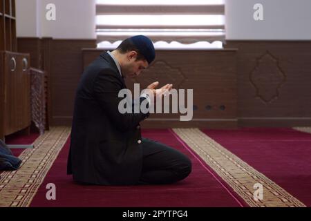 Young Muslim man kneeling and praying alone in a mosque. 12 November, 2019. Kyiv, Ukraine Stock Photo