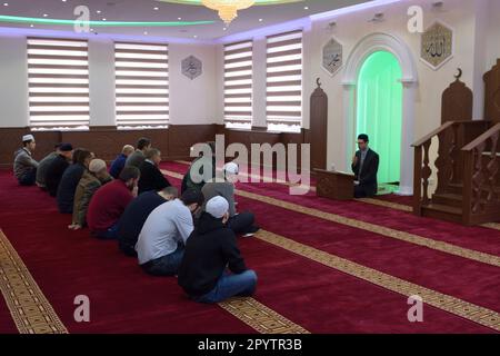 Group of Muslim men kneeling and listening to mullah preaching in a mosque. 12 November, 2019. Kyiv, Ukraine Stock Photo
