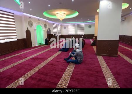 Group of Muslim men kneeling and listening to mullah preaching in a mosque. 12 November, 2019. Kyiv, Ukraine Stock Photo