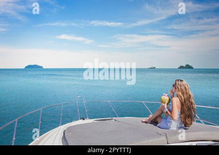 luxury travel, woman relaxing on luxurious boat and drinking coconut, vip sea cruise Stock Photo