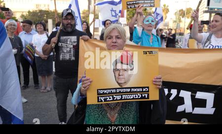 A right-wing protestor holds a sign with the image of former High Court Justice president Aharon Barak with a red Fez hat, traditionally worn by Moroccans during a demonstration held by Moroccan Jews near the home of former High Court Justice president Aharon Barak, in response to his past claims that he could “not find a single” Moroccan or Mizrahi judge to serve on the supreme court on May 4, 2023 in Tel Aviv, Israel. Stock Photo