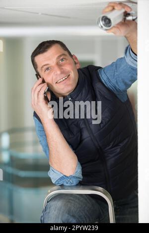 technician installing a cctv on the ceiling Stock Photo